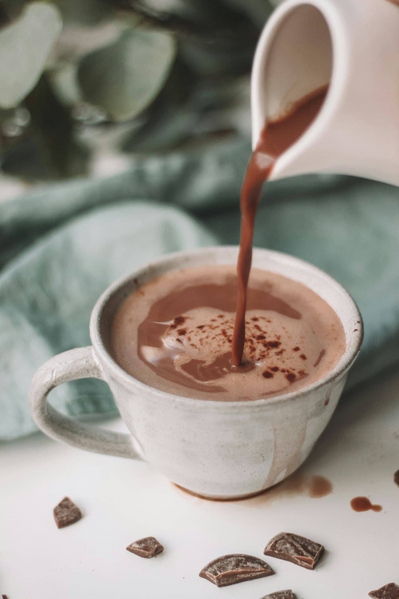 Hot chocolate poured from a jug into a ceramic cup