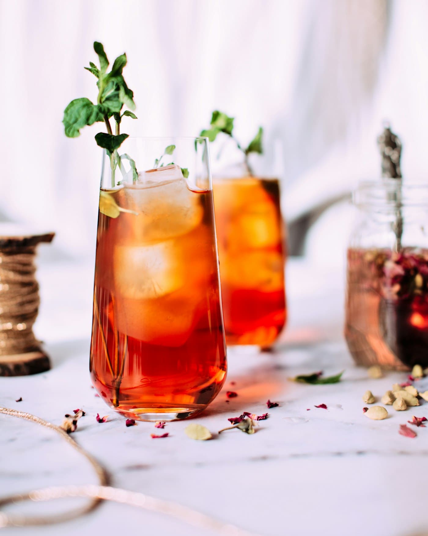 Two glasses of iced tea with mint and citrus on a marble surface