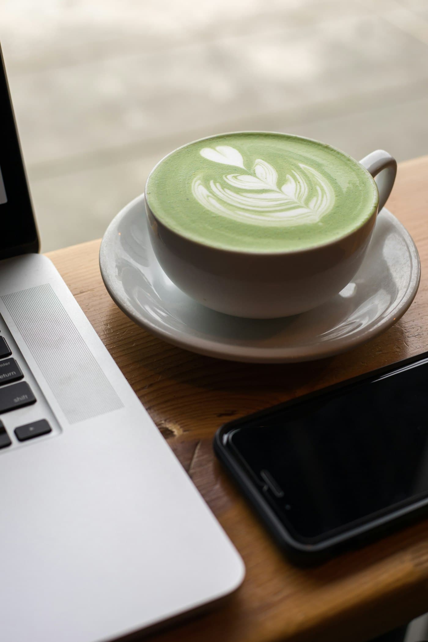 A matcha latte with leaf latte art in a ceramic cup