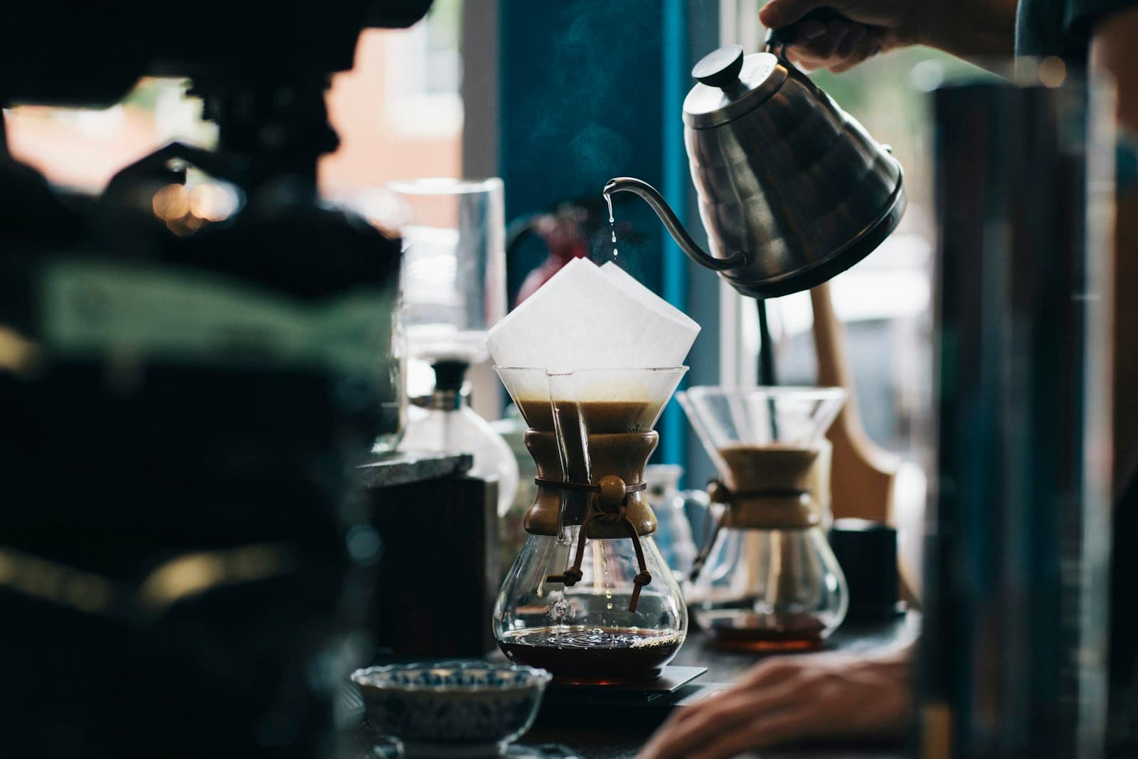 Hot water poured from a gooseneck kettle over a Chemex brewer