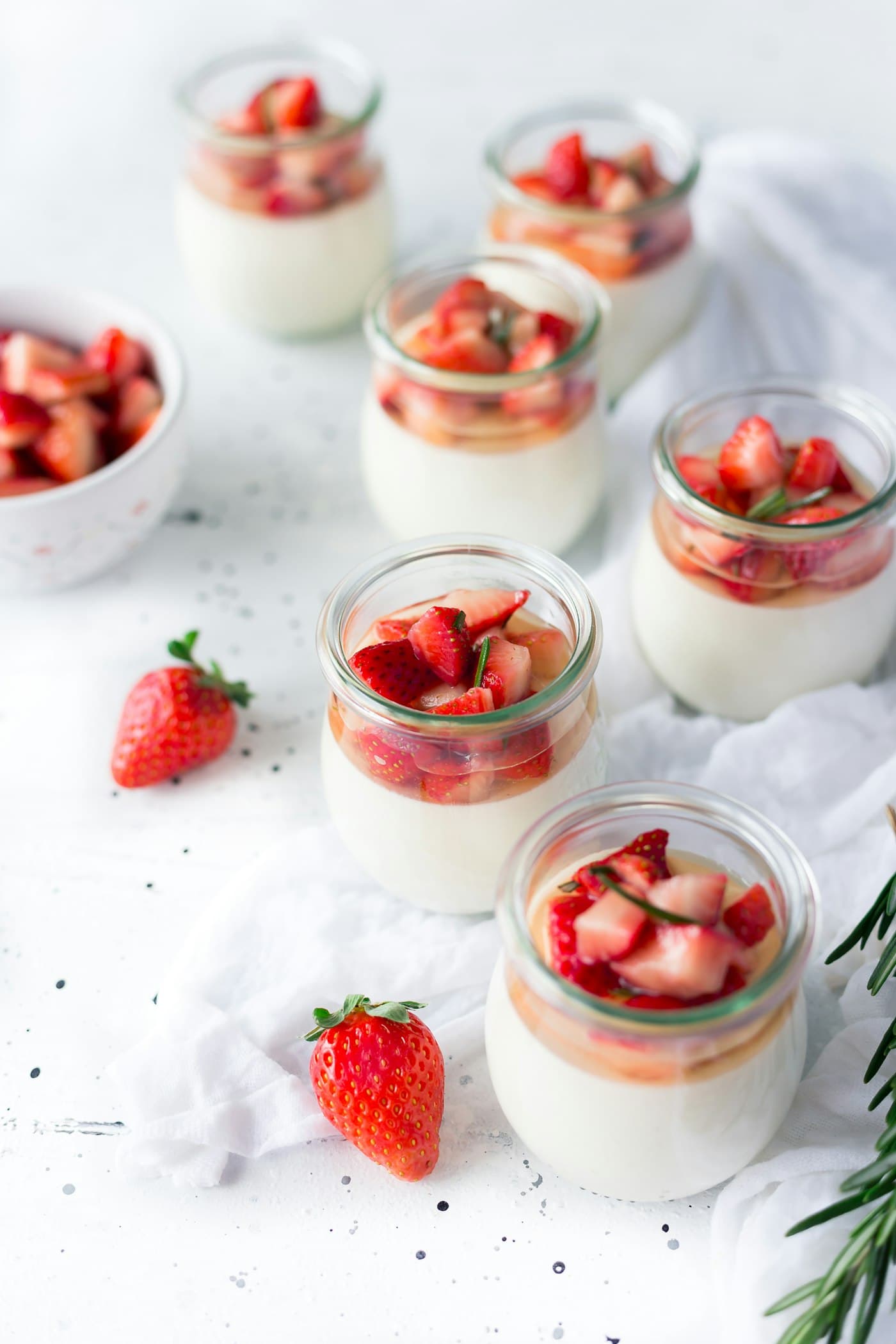 Jars of yoghurt layered with granola and fresh strawberries