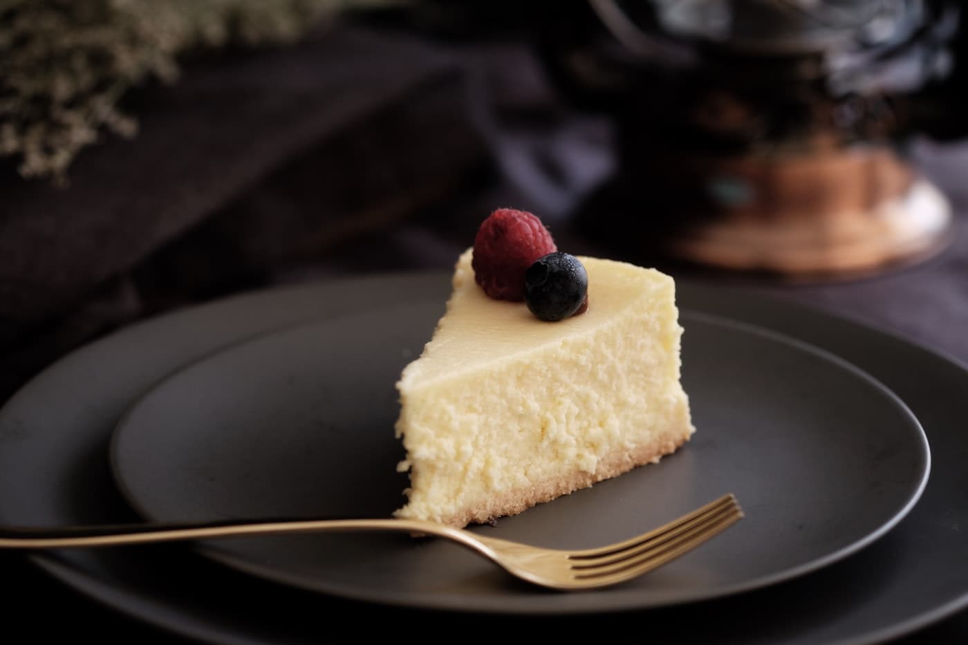 A slice of burnt Basque cheesecake with berries on a dark plate