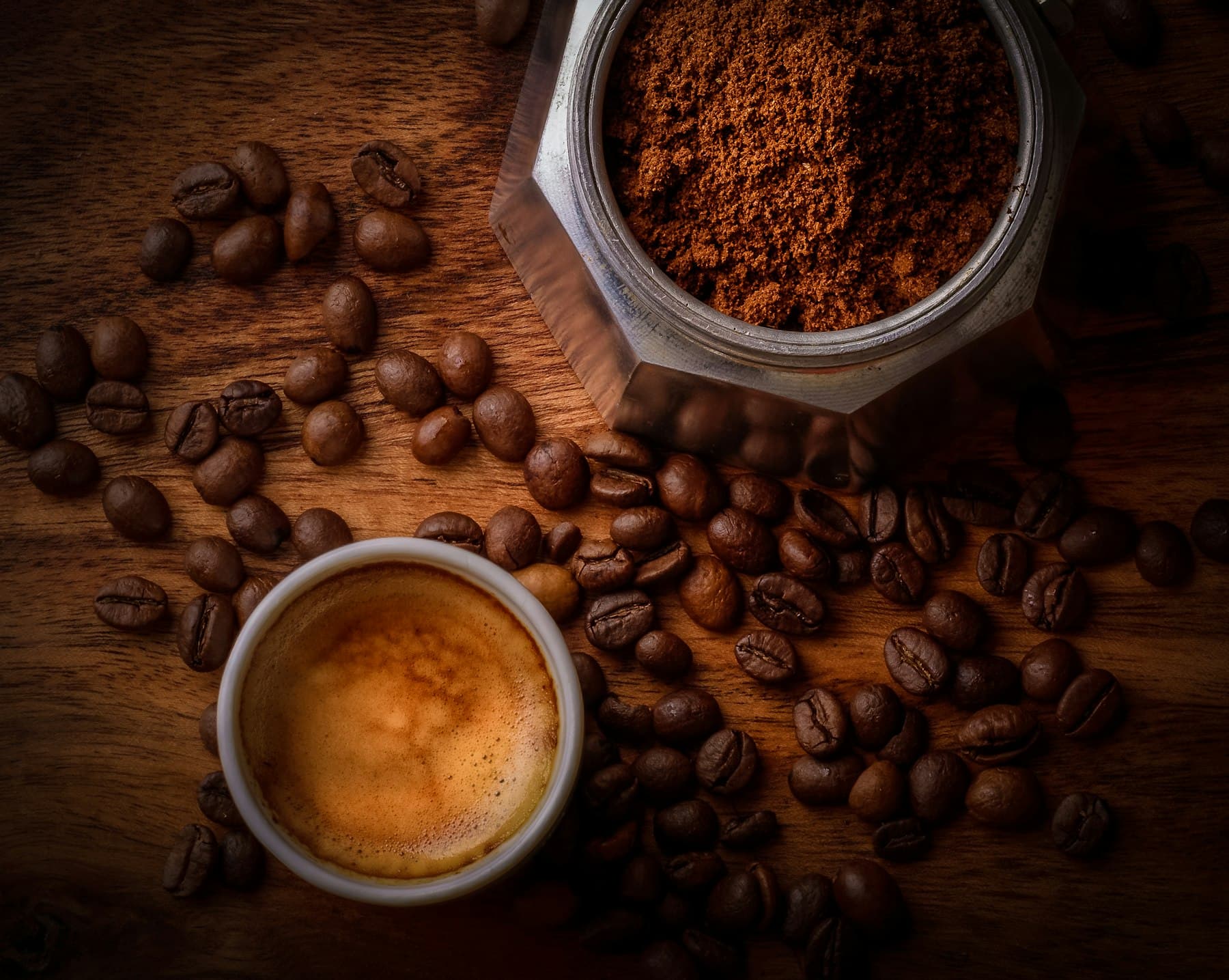 A portafilter of ground coffee beside a fresh espresso shot