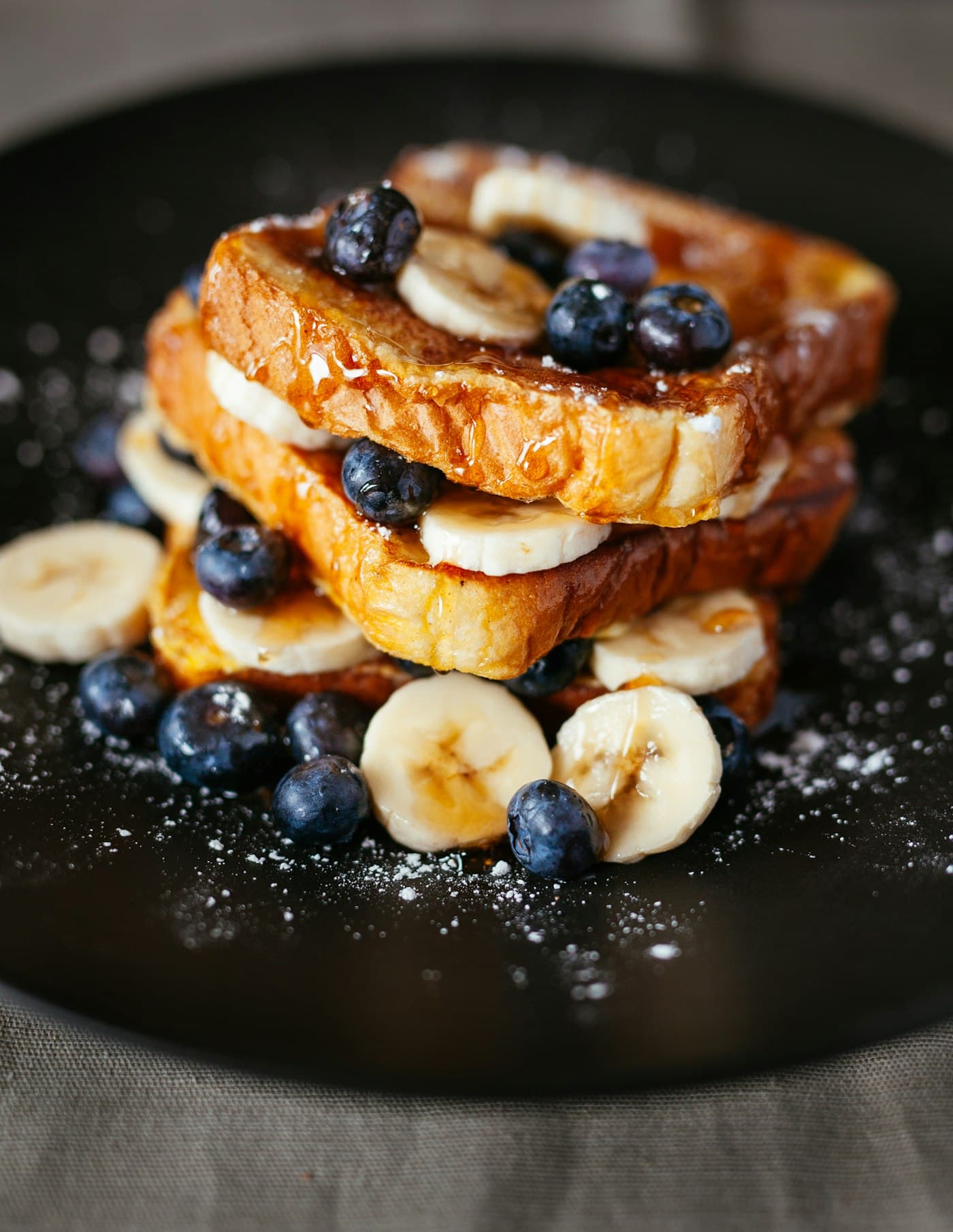 French toast stacked with banana, blueberries and maple syrup