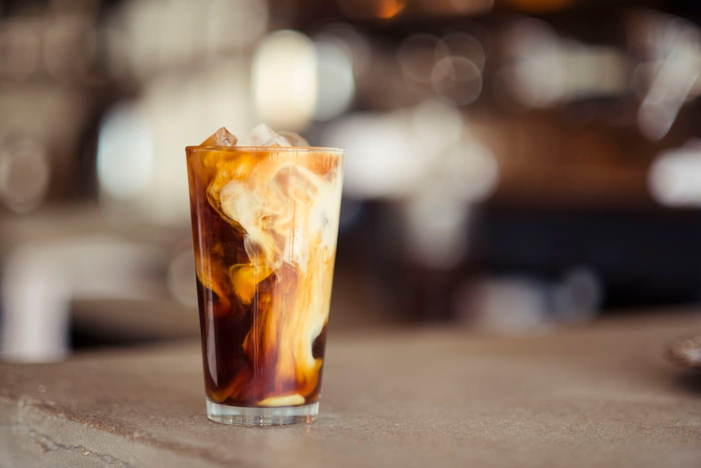 Cold brew over ice with cream swirling through the glass