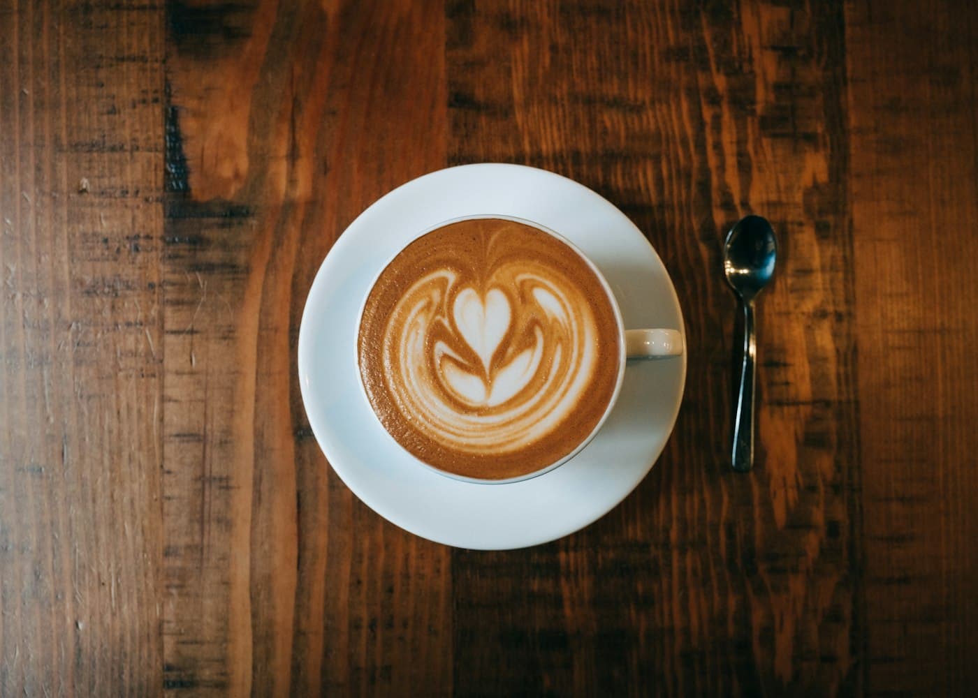 Cappuccino with rosetta latte art on a warm wooden table