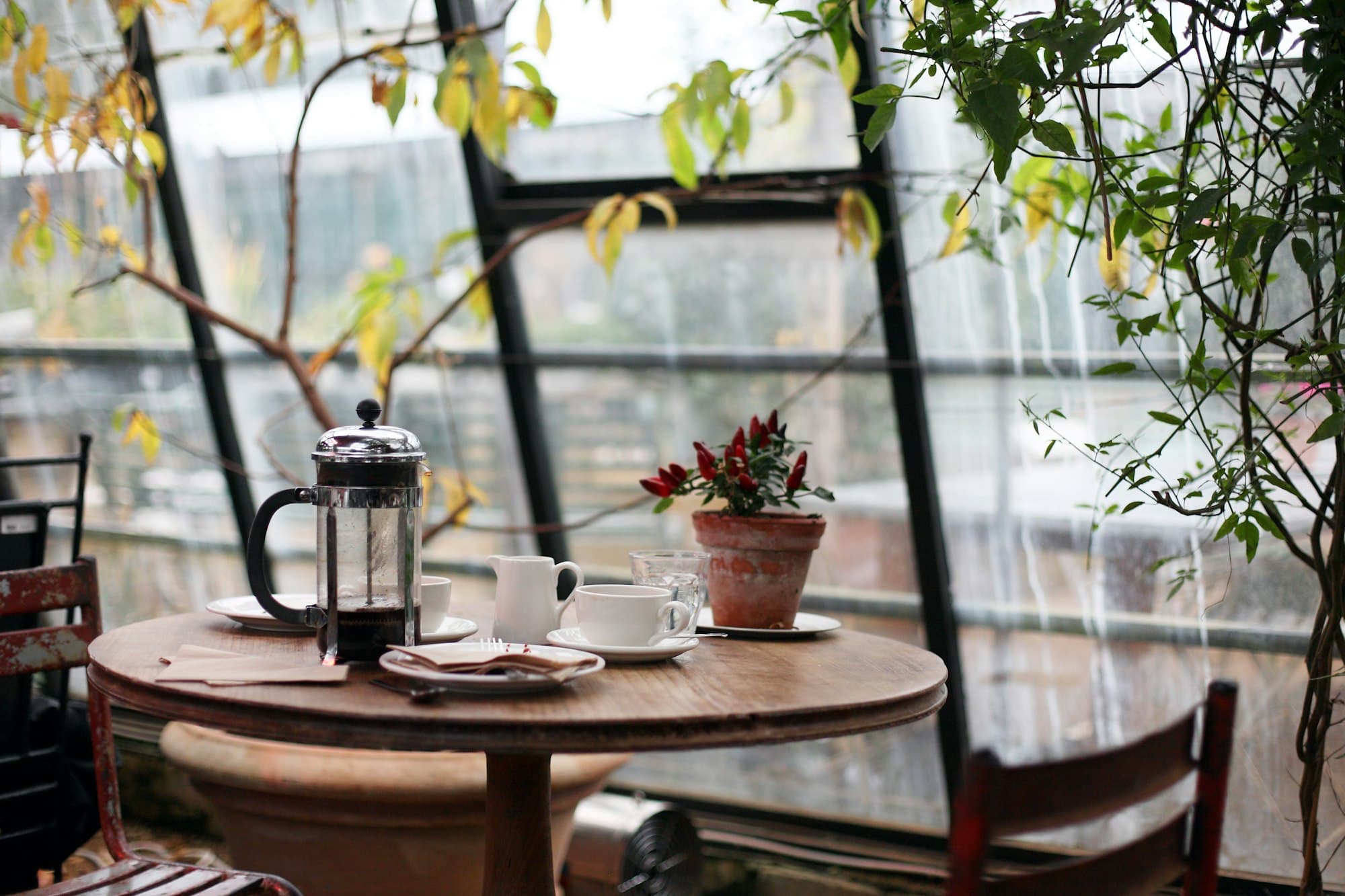 A French press and espresso cups on a round table by the window in the morning