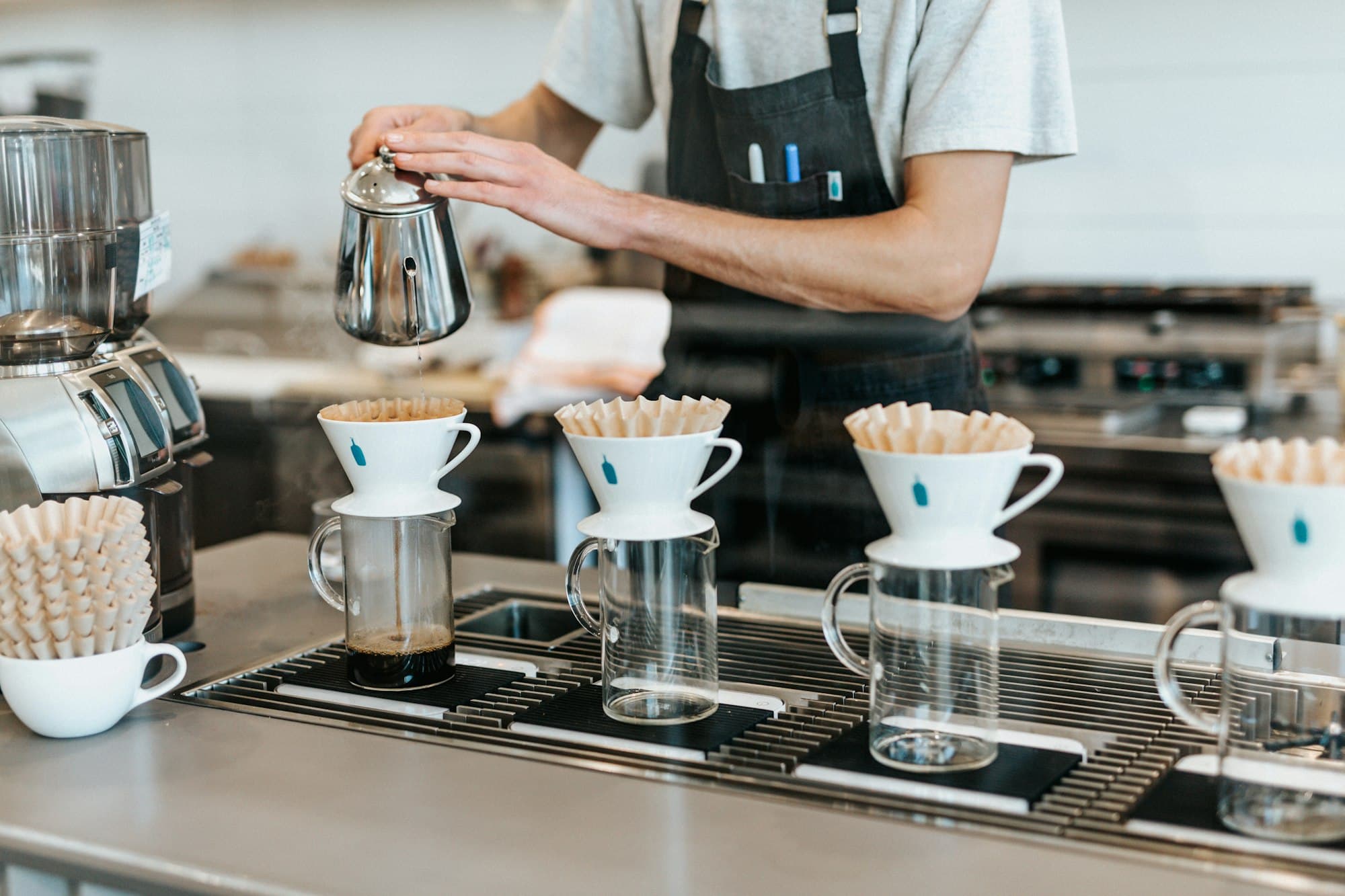 A barista brewing a row of V60 pour-overs in the morning light at the Morrow & Bean coffee bar